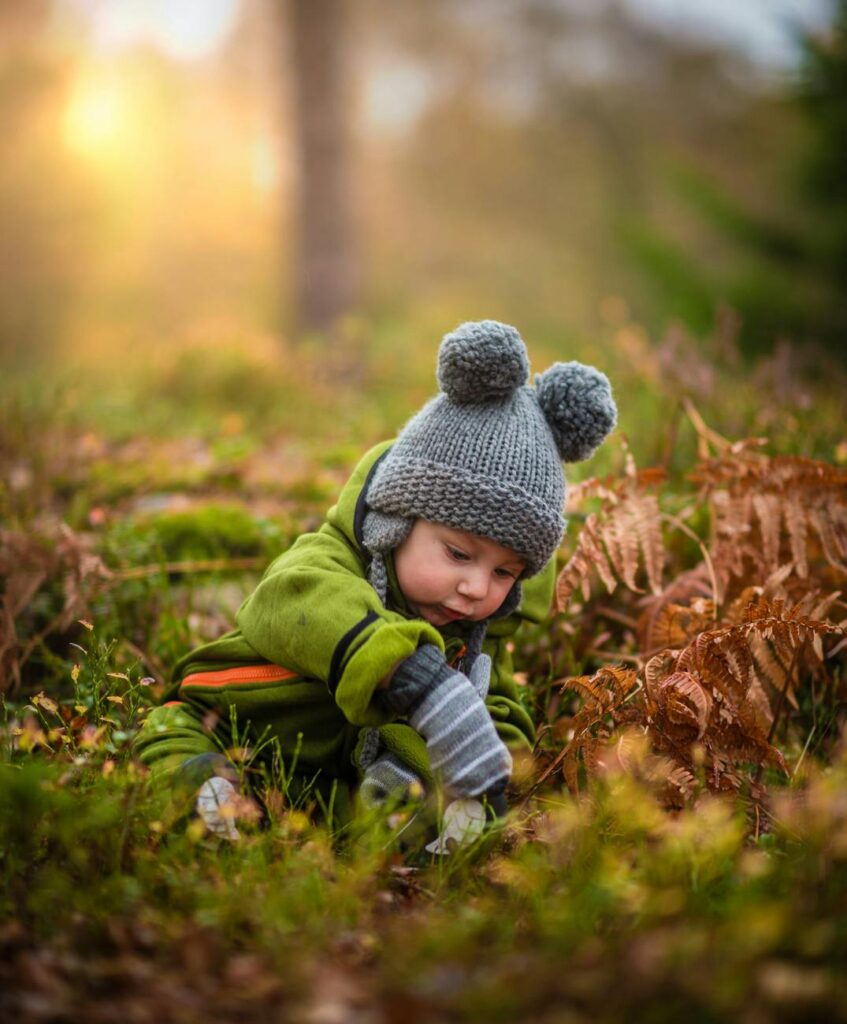 pexels-photo-590471-590471 A cute baby in a knit hat and green outfit exploring nature during sunset.